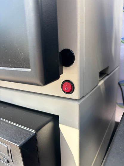 Close-up of a metallic surface with a red power button and black circular component.