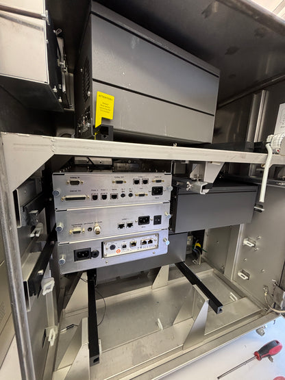 Close-up of electronic equipment inside a machine with visible components and a yellow label.