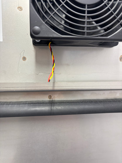 Black fan attached to a metallic surface with visible wiring.