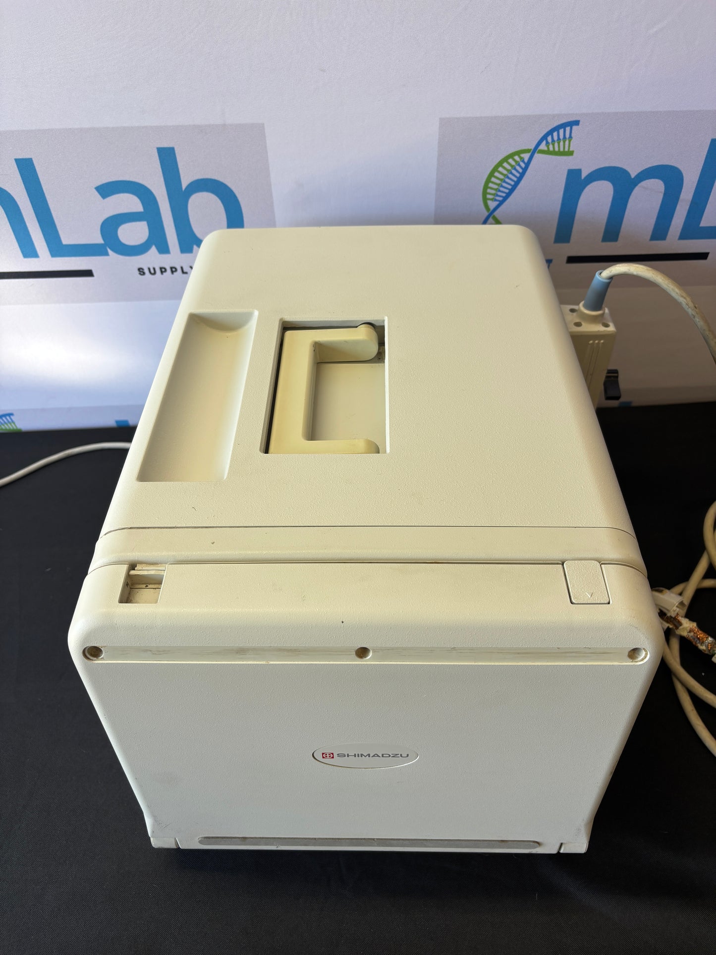 White electronic device mounted on a wall with a visible brand logo in the background.