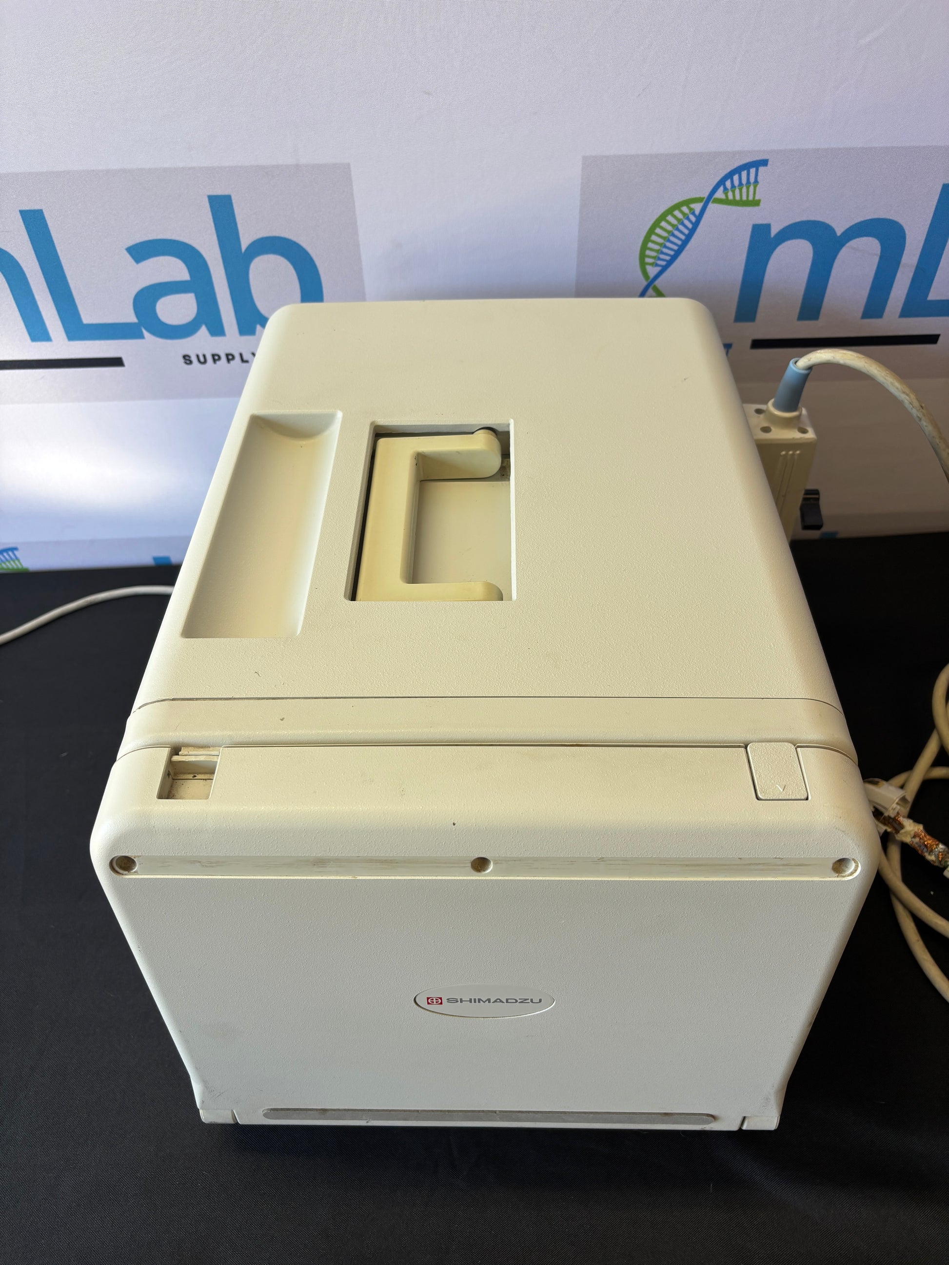 White electronic device mounted on a wall with a visible brand logo in the background.