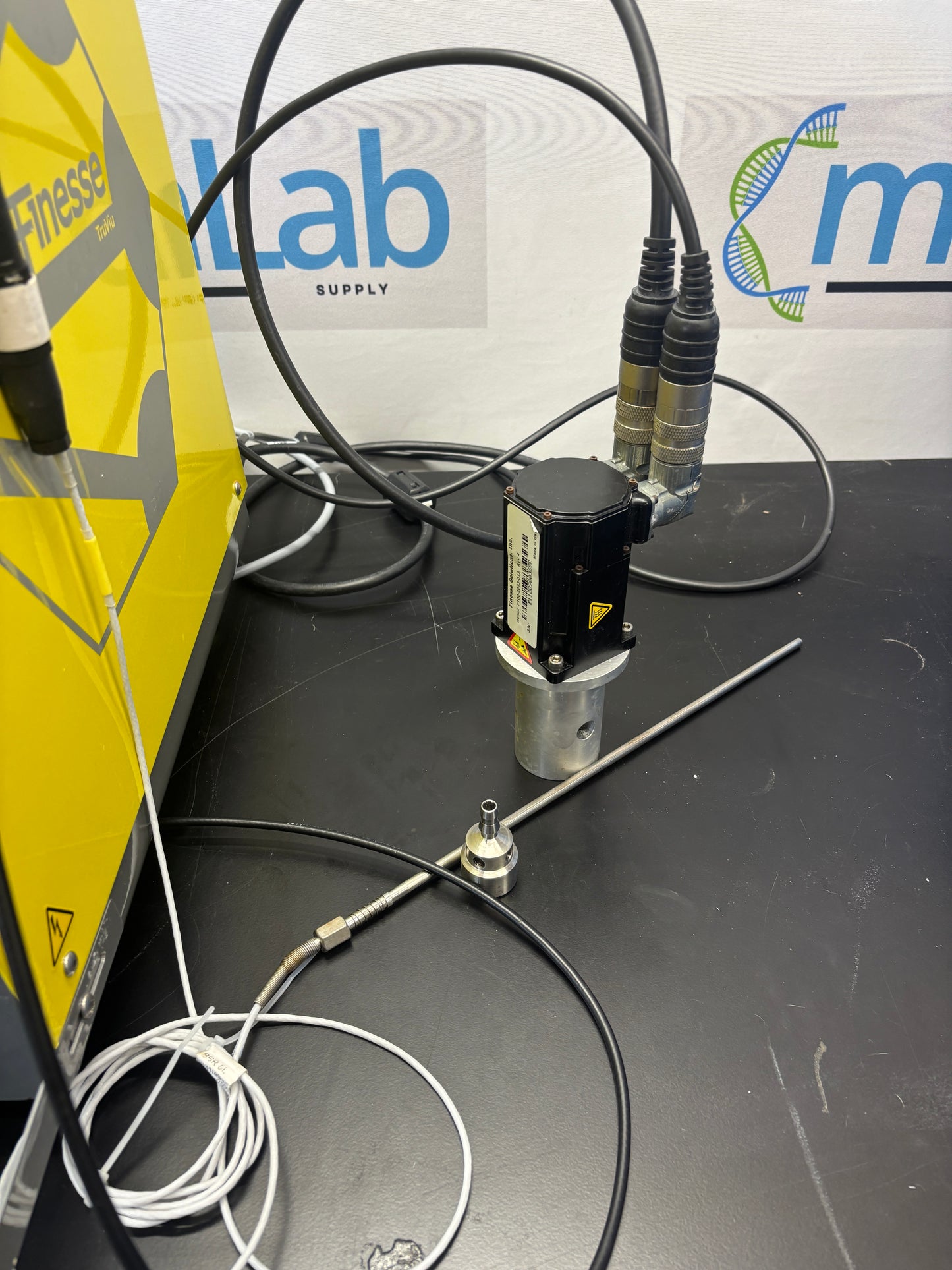 Technical setup with cables and equipment on a black surface, featuring a visible brand logo.