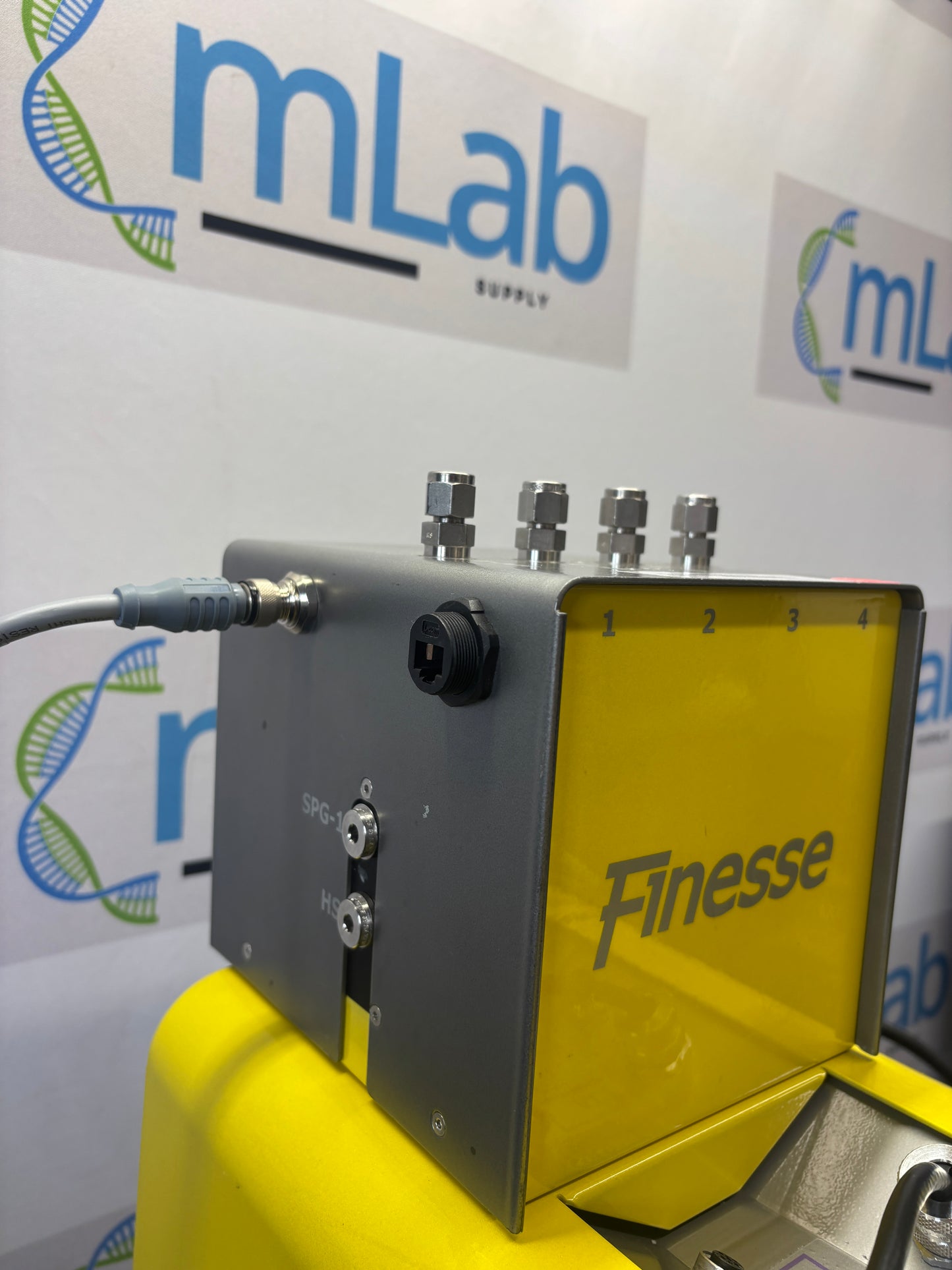 Yellow and gray device labeled 'Finesse' with 'mLab' branding in the background