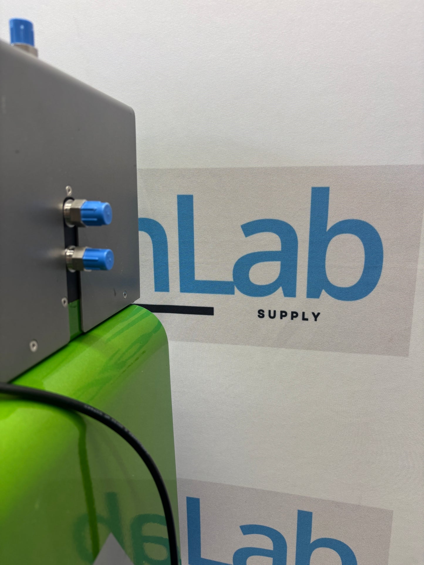Green machine with blue knobs against a white wall with 'Lab Supply' branding.