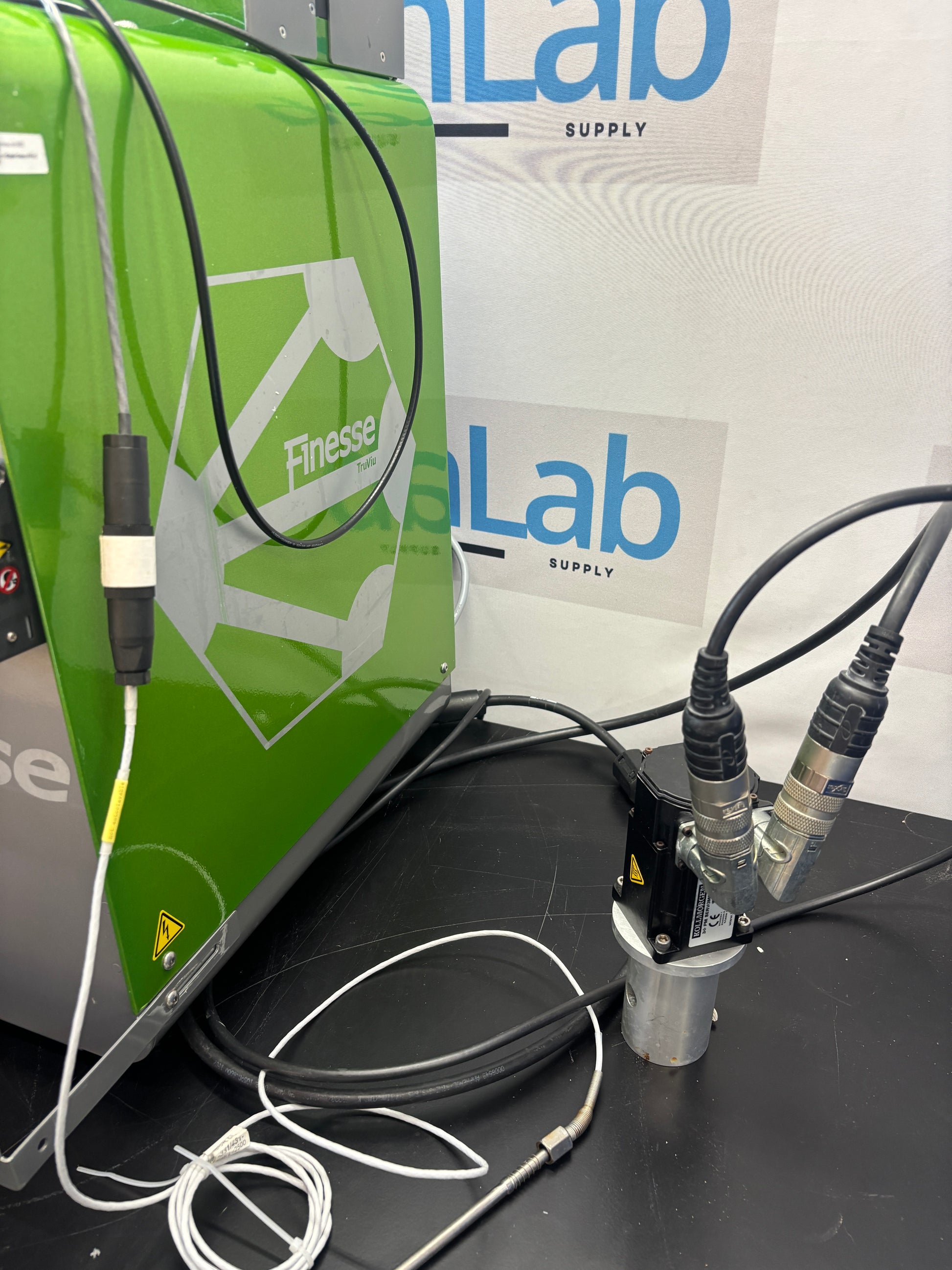 Close-up of electronic equipment with cables on a surface, featuring a brand logo.