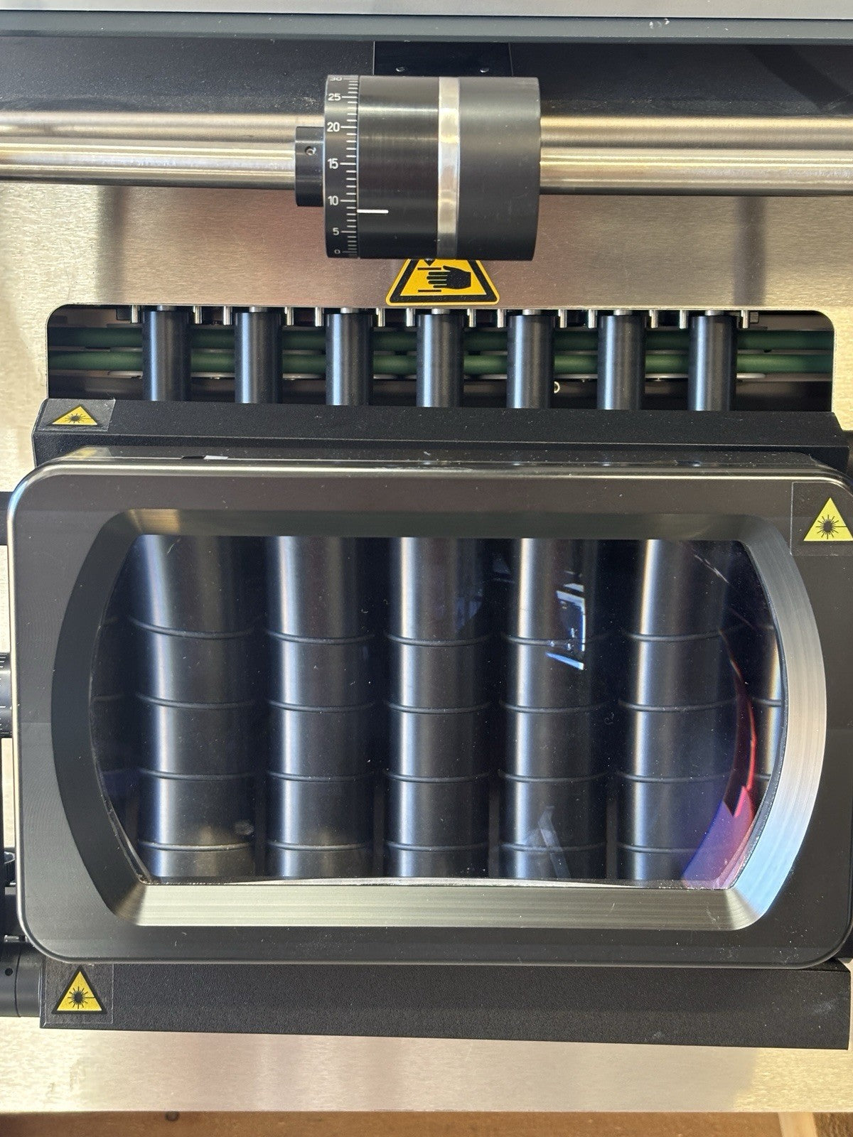 Close-up of a machine with cylindrical components and warning labels.