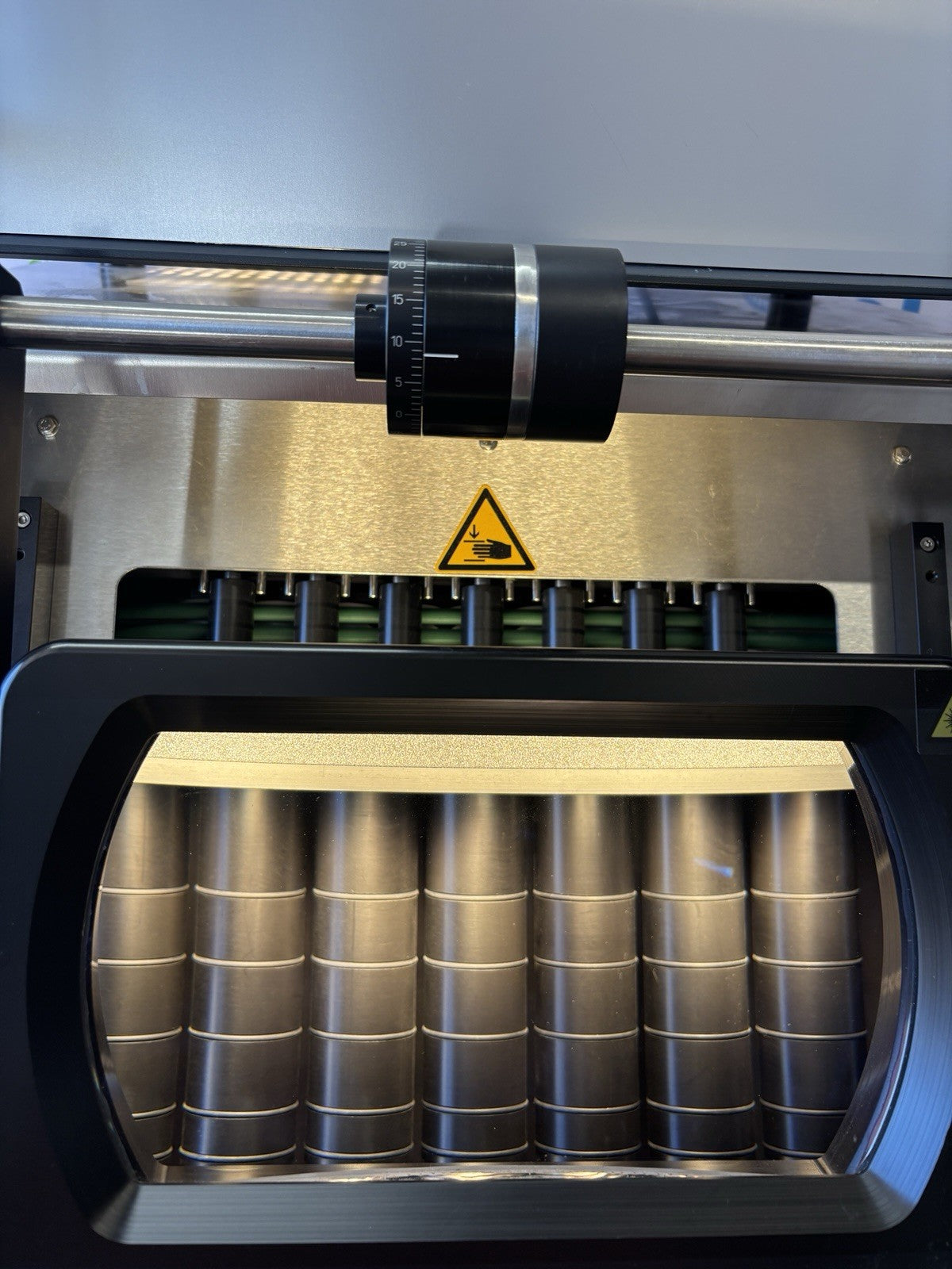 3D printer in operation with a warning label on the bed