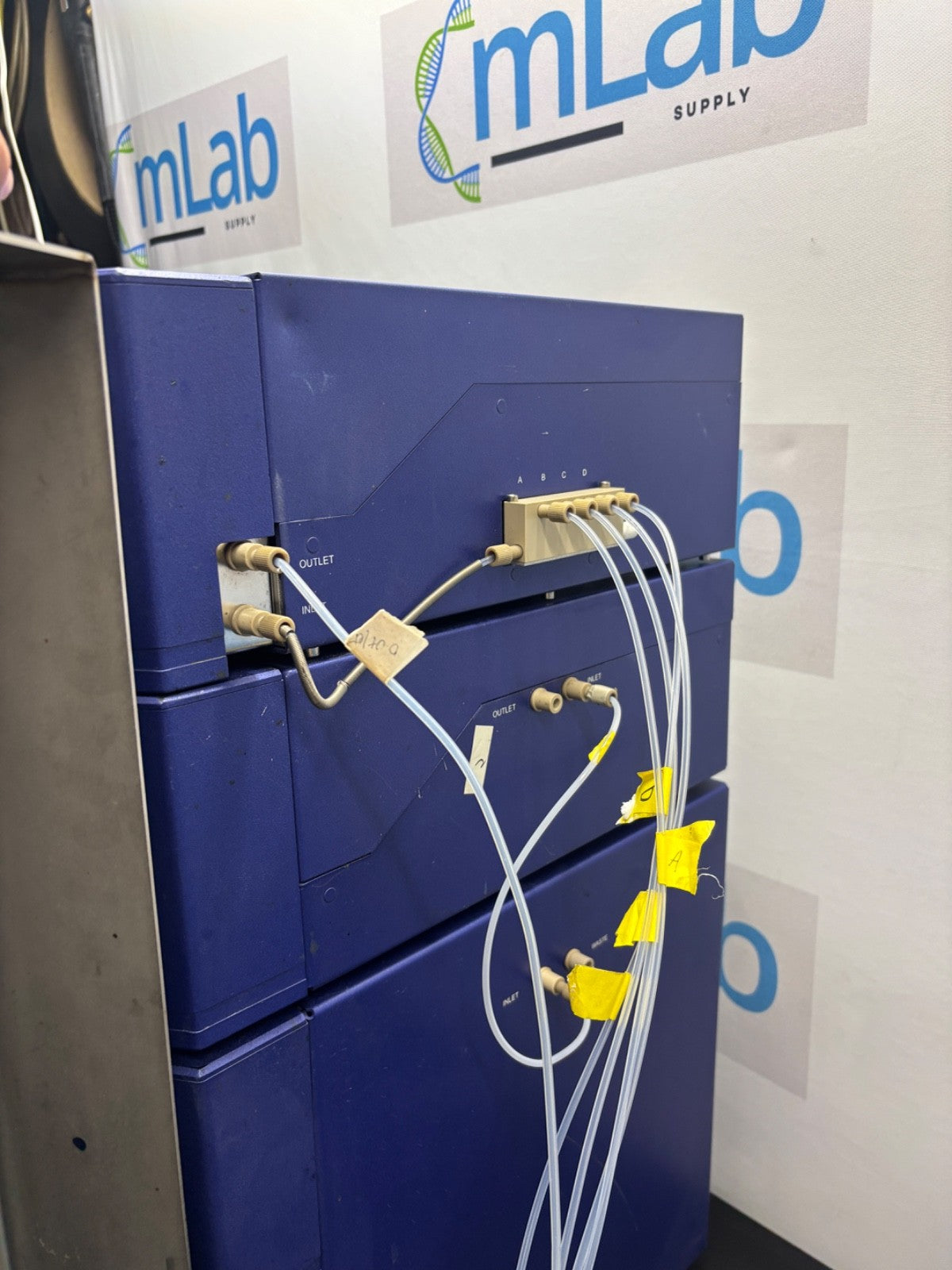 Blue 3D printer with hoses and connectors, branded 'mLab Supply' in the background.