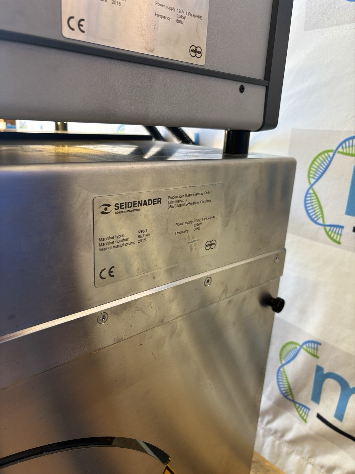 Metallic machine with Seidenader branding and certification logos on a white background with logos.