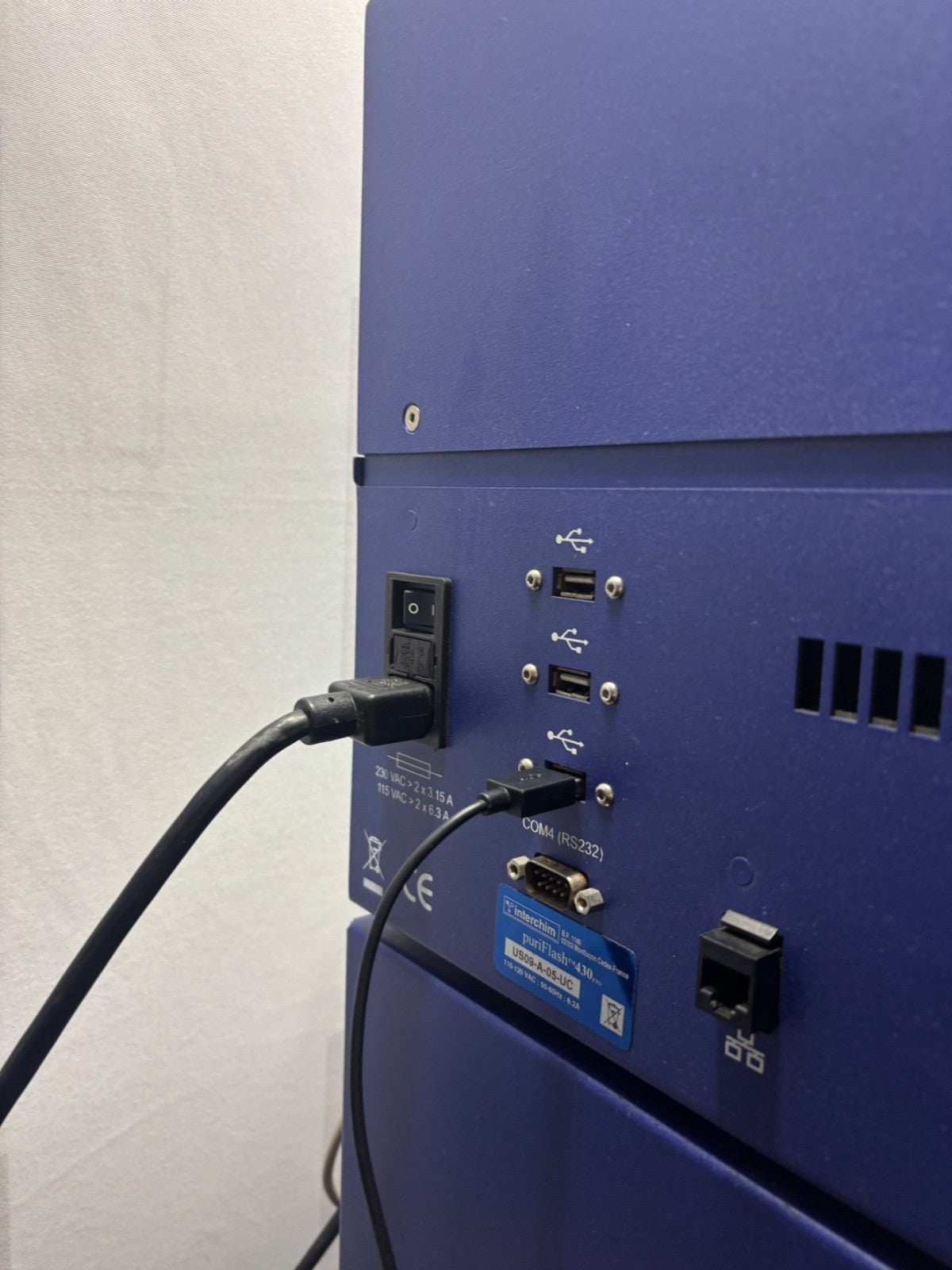 Back view of a blue electronic device with ports and cables on a light gray background